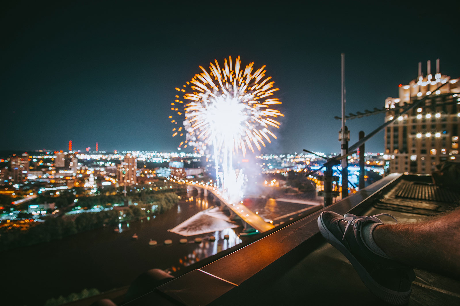 man viewing fireworks in a city from the roof